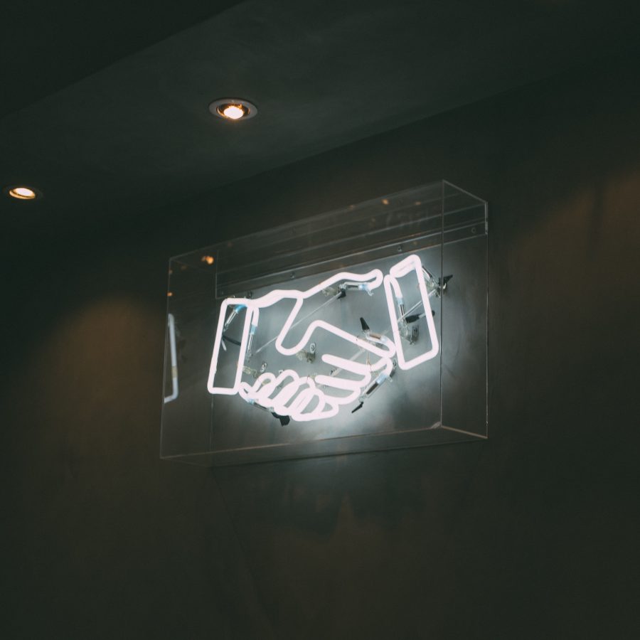 neon sign of hands shaking